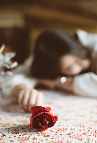 手拿玫瑰花趴着思考的女孩